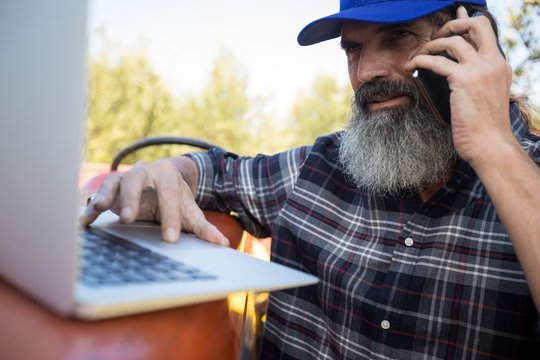 Man using laptop while talking on mobile phone - Powered by Adobe