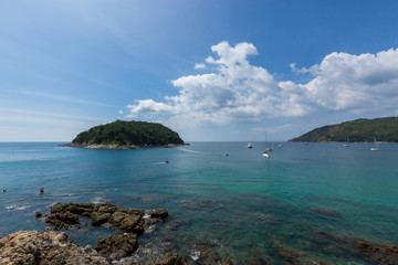 Obraz premium Jungle island surrounded by sailboats, clear water and blue skies.