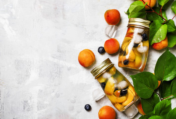 Cold drink with apricot, blueberry and ice, gray  background, top view