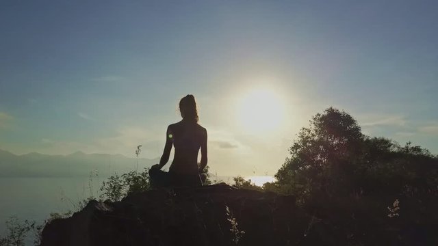 Drone Rotates around Woman Silhouette in Padmasana on Cliff