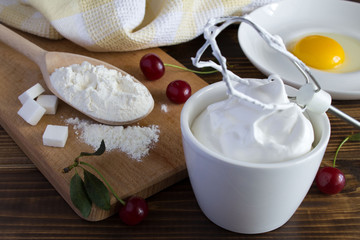 Ingredients for biscuit with cherries on the brown wooden background