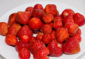 Fresh harvest of strawberries. Ripe fresh strawberries on a white plate