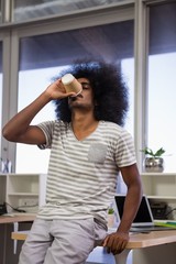 Fototapeta na wymiar Young man drinking coffee at office