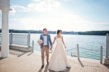 Stunning wedding couple walking on lakeside on a sunny day.