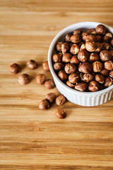 Peeled hazelnuts in a white bowl, vertical composition