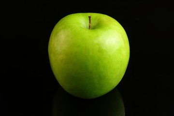 A fresh Granny Smith apple on a black background.