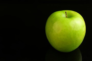A fresh Granny Smith apple on a black background.