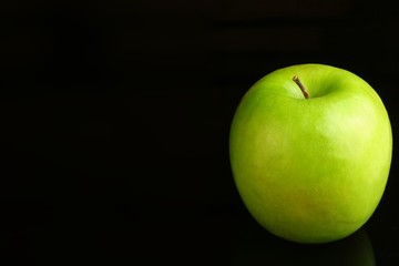 A fresh green apple on a black background.