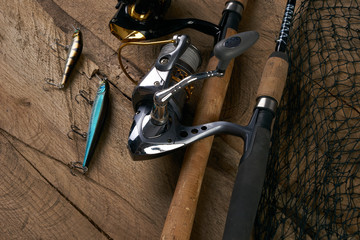 Fishing equipment - fishing spinning, hooks, lures and fishnet on dark wooden background.Top view.