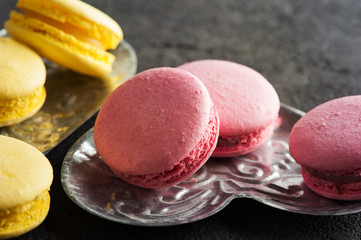Closeup of yellow pink macaroons on black concrete