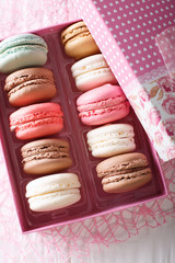 Multicolored macaroons in a gift box close-up on a table. Vertical view from above