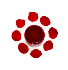 red cup of african rooibos red tea with rose petals on white background, top view
