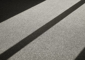 Fototapeta premium Schatten durch einfallendes Licht auf einem Teppichboden vor einem Fenster