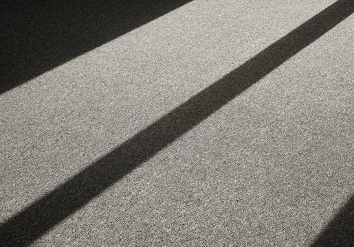 Schatten durch einfallendes Licht auf einem Teppichboden vor einem Fenster