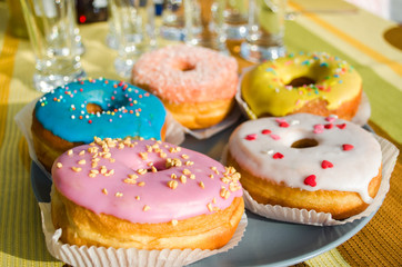 Assorted donuts in the glaze on the festive table. Sweet pastries.