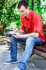 Obraz premium student boy posing looking at you sitting on the grass in a park