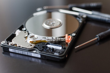 Obraz premium Repair of the dismantled hard drive. Hdd with mirror effect. Screwdrivers for computer repair.