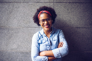 Young woman standing with her arms crossed against a wall