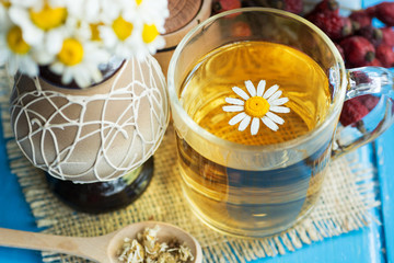 Obraz na płótnie Canvas cup of herbal chamomile tea with fresh daisy flowers on blue wooden background. doctor treatment and prevention of immune concept, medicine - folk, alternative, complementary, traditional medicine 