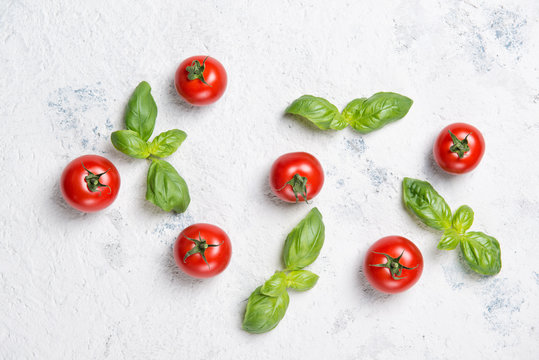 Fresh cherry tomatoes with basil leaves on a stone table, vegetable pattern, top view
