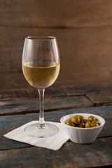 Green olives in container by white wine