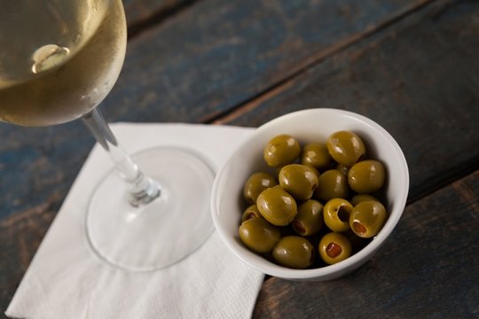Cropped image of wineglass by green olives served in container