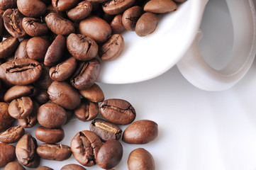 Close-up of spilled coffee beans from a cup on a saucer