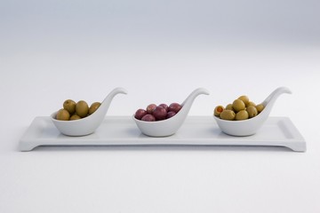 Various olives in container on white background