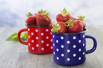Bright ripe strawberry  in a metal cups  on a light background.