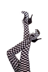 A pair of motorsport legs are stretched out high in a vertical  form in front of a white background. The womans stockings  and high heels have a checkered race flag design.