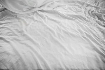 Crumpled white sheets on morning bed. Background white creased cloth. Texture of the fabric after sleep.