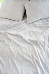 Crumpled white sheets and pillows, morning bed kept warmly bodies. Background white creased cloth. The texture of the fabric after sleep.