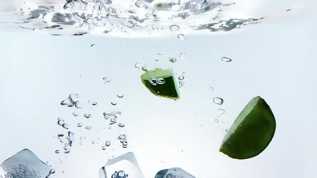 lime fruit and ice cubes splash falling down into white cocktail and water drinking glass, shot in slow motion on white background, fun, nutrition and drink concept