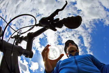 cyclist with a bike with a bottle of water on sky background.