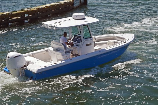 A small open sport fishing boat powered by a single outboard engine cruising the florida intra-coastal waterway near Miami Beach.