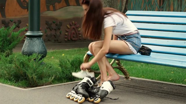 a young girl is sitting on a bench in the Park removed the rollers
