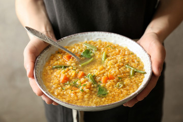 Young woman holding plate with tasty lentil dish, closeup
