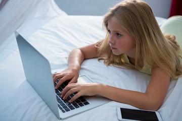 Girl using laptop on bed