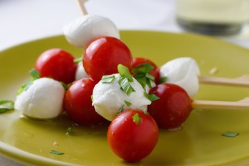 Caprese salad in the form of skewer made from cherries of mozzarella cheese, cherry tomatoes, basil and olive oil on bamboo stick