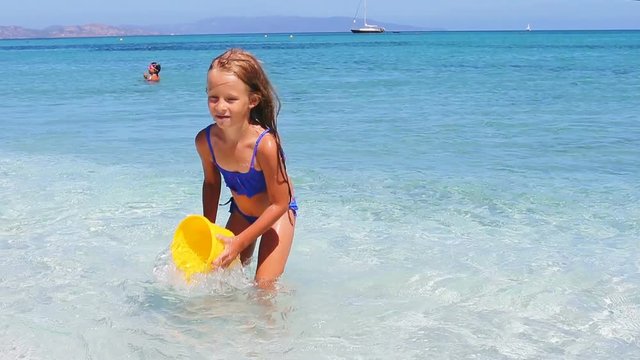 Adorable little girl have fun with beach toys in shallow water at tropical beach