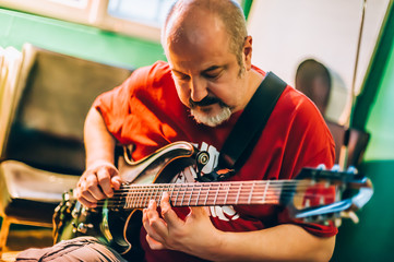 Behind scene. Guitarist practice playing guitar in messy music studio