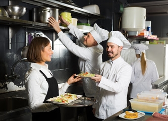 Young female waiter taking ordered dishes