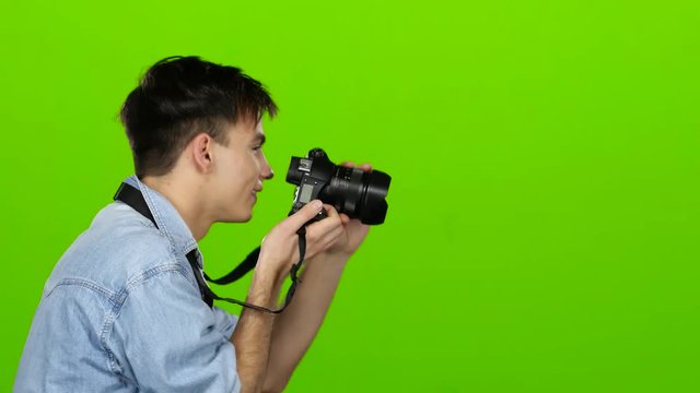 Guy is holding a camera and making beautiful pictures of others. Green screen
