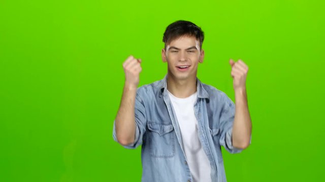 Young guy is happy with his victories, he is happy. Green screen