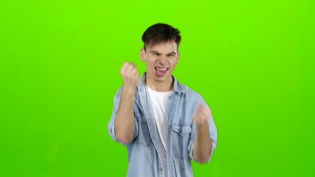 Young guy is happy with his victories, he is happy. Green screen. Slow motion
