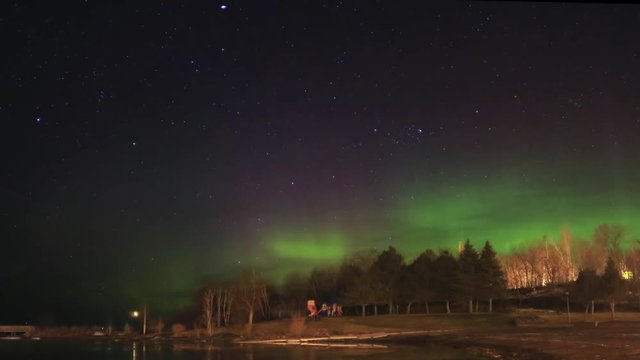 Aurora with green, purple and red light dancing in northern sky over a small park in Georgian Bay, Northern Ontario, Canada