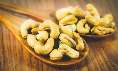 Close up pile of cashew nuts wood spoon on wood background, cashew nuts perfect for a diet for a healthy diet and can be used as medicine. concept: diet, fitness, medicine.