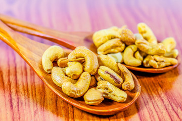 Roasted cashew nuts on a wooden spoon.Roasted salted cashew nuts on white background. Healthy food, cashews rich in heart friendly fatty acids. Cashew nuts as food background.