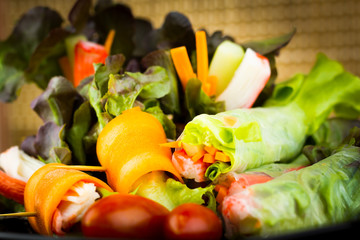 Close up of fresh salad of lettuce, cucumber and tomato on plate for healthy eating...Fresh vegetable salad in Black plate  on wood table. Salad for healthy. Fresh raw vegetables salad background.