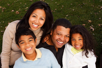 Biracial family laughing and smiling outside. - Powered by Adobe